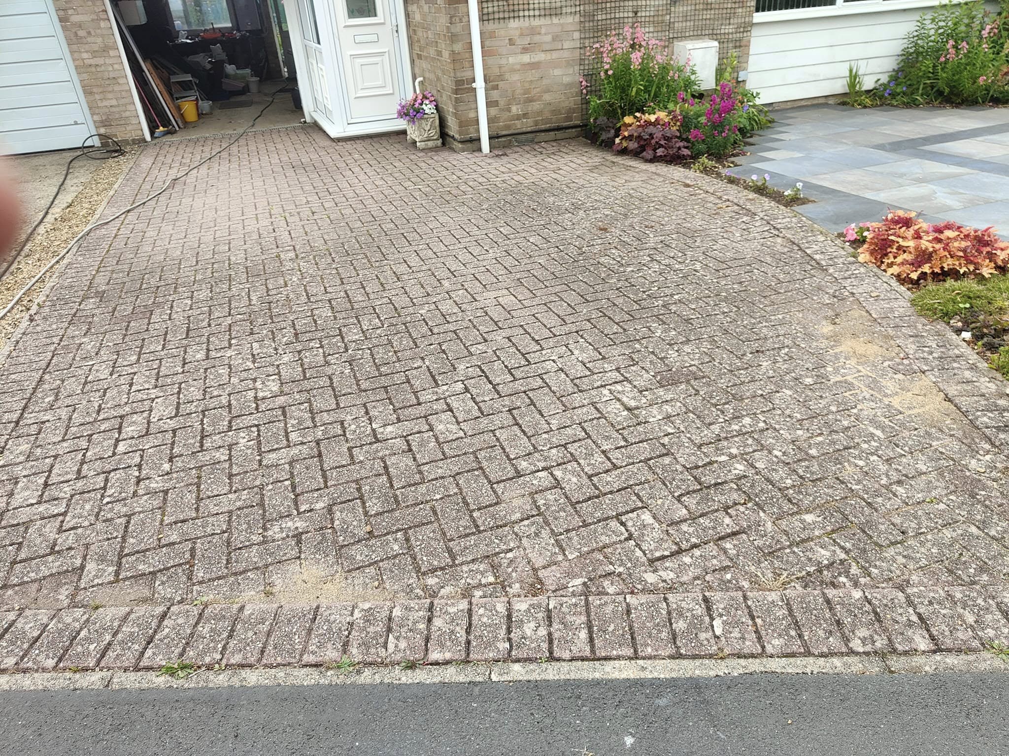 Grey, weathered block paving drive before cleaning