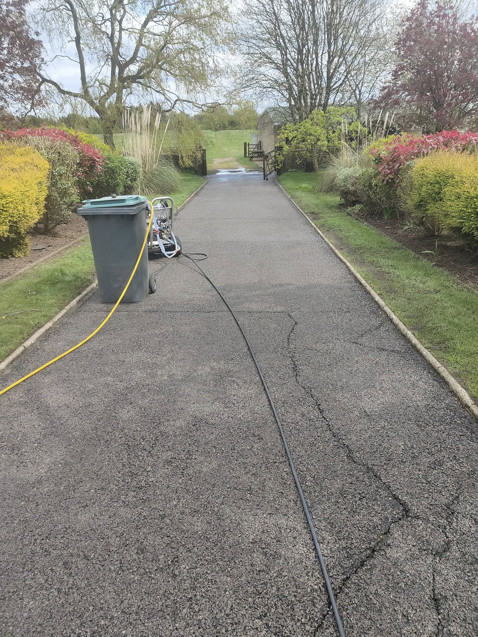 Jet wash hose laid along a long garden path mid-clean
