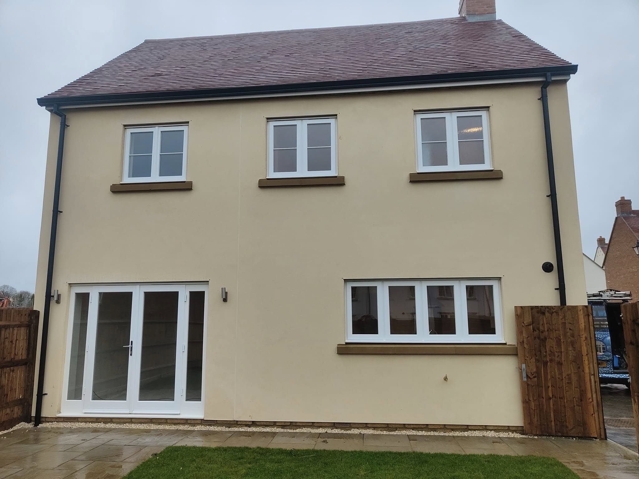 Rear of a cream rendered new-build house with clean windows and French doors