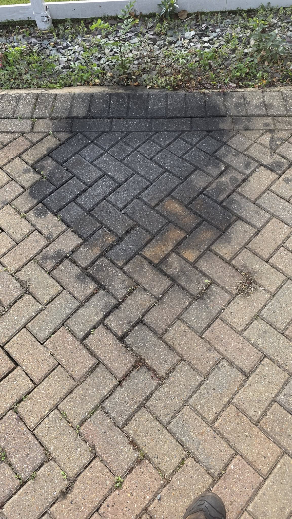 Block paving drive with a large dark engine oil stain